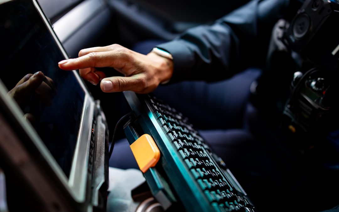 A police officer uses mobile data terminal in a patrol car.