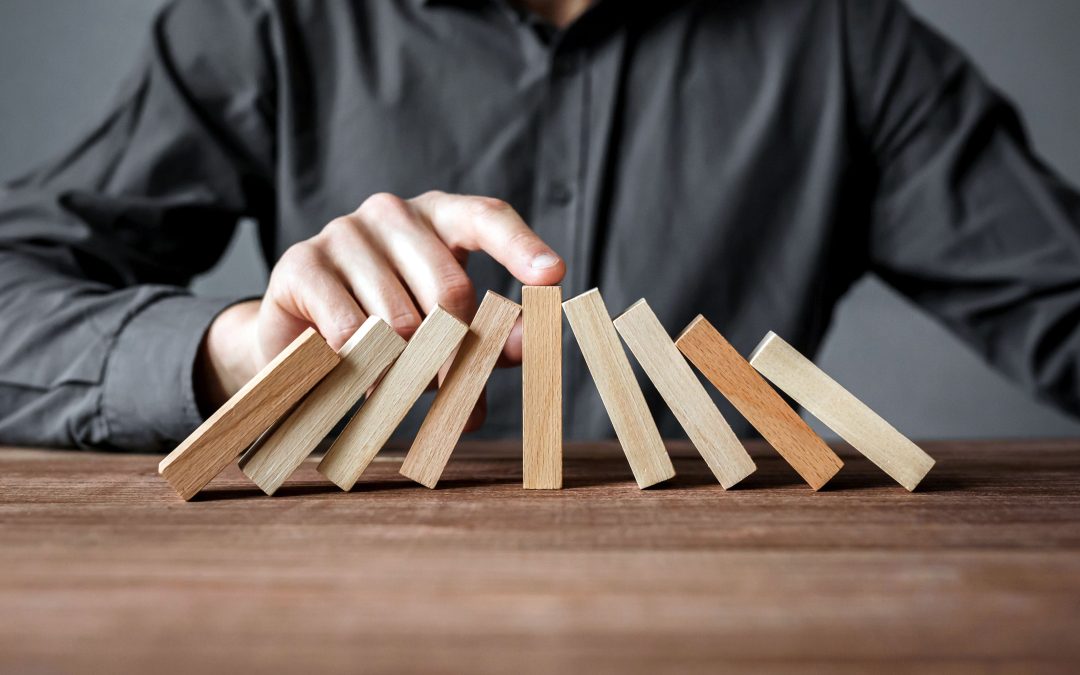 A finger holds a block steady while other blocks lean into it from either side.