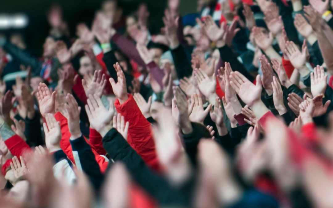 A photo of hands raised throughout a large crowd at a concert or sports game.