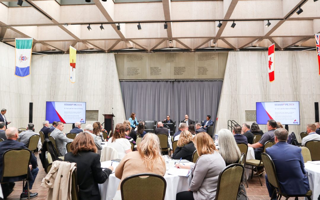 an event space of conference attendees watching a panel of presenters speak