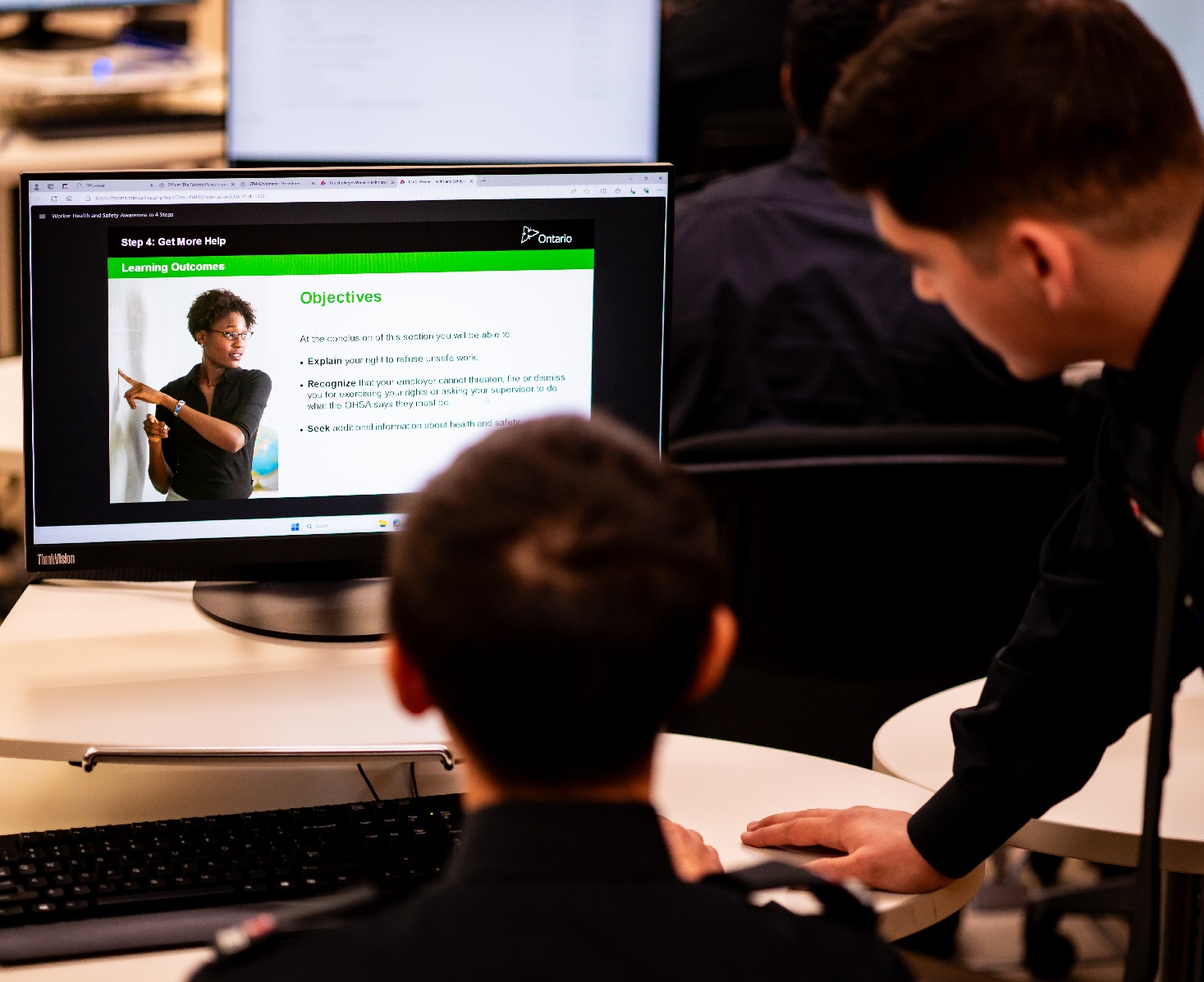 Two police cadets view an online course displayed on a computer.
